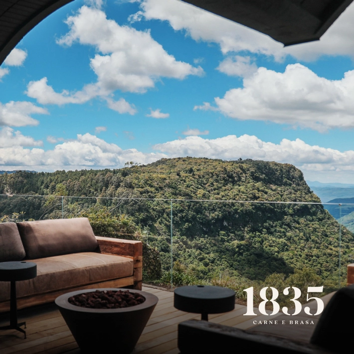 Área externa com sofá e vista panorâmica para as montanhas na laje de pedra.