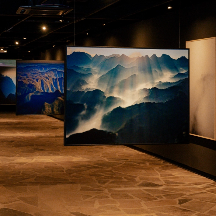 Exposição de arte com fotografias de paisagens montanhosas na laje de pedra.