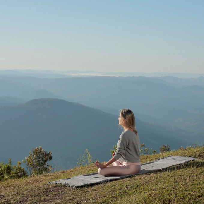 Mulher meditando em frente à vista panorâmica de um apartamento na Serra Gaúcha